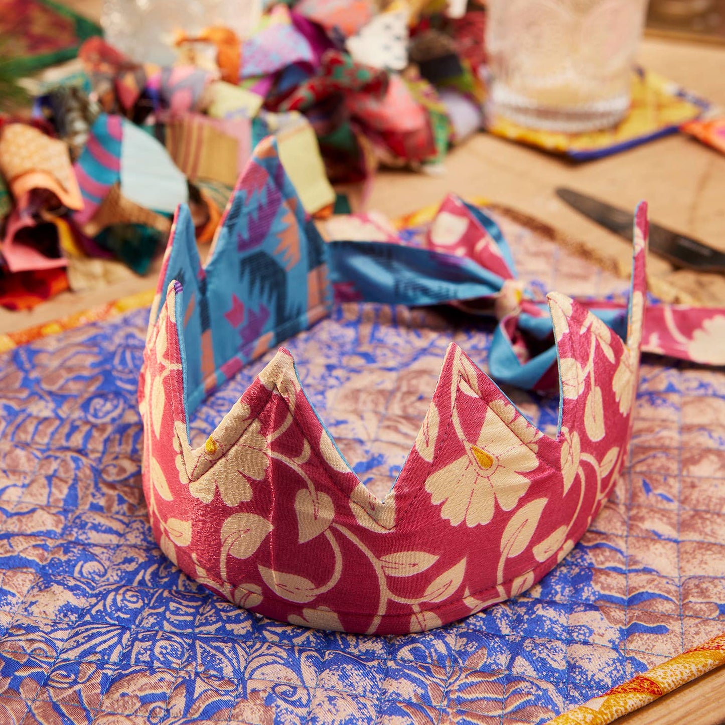 Decorative fabric christmas crown on a table with colorful materials in the background