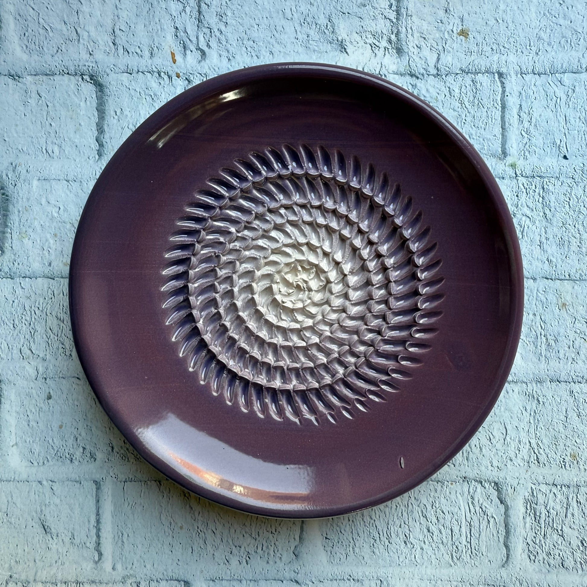 Purple ceramic plate with a decorative pattern on a textured light blue background