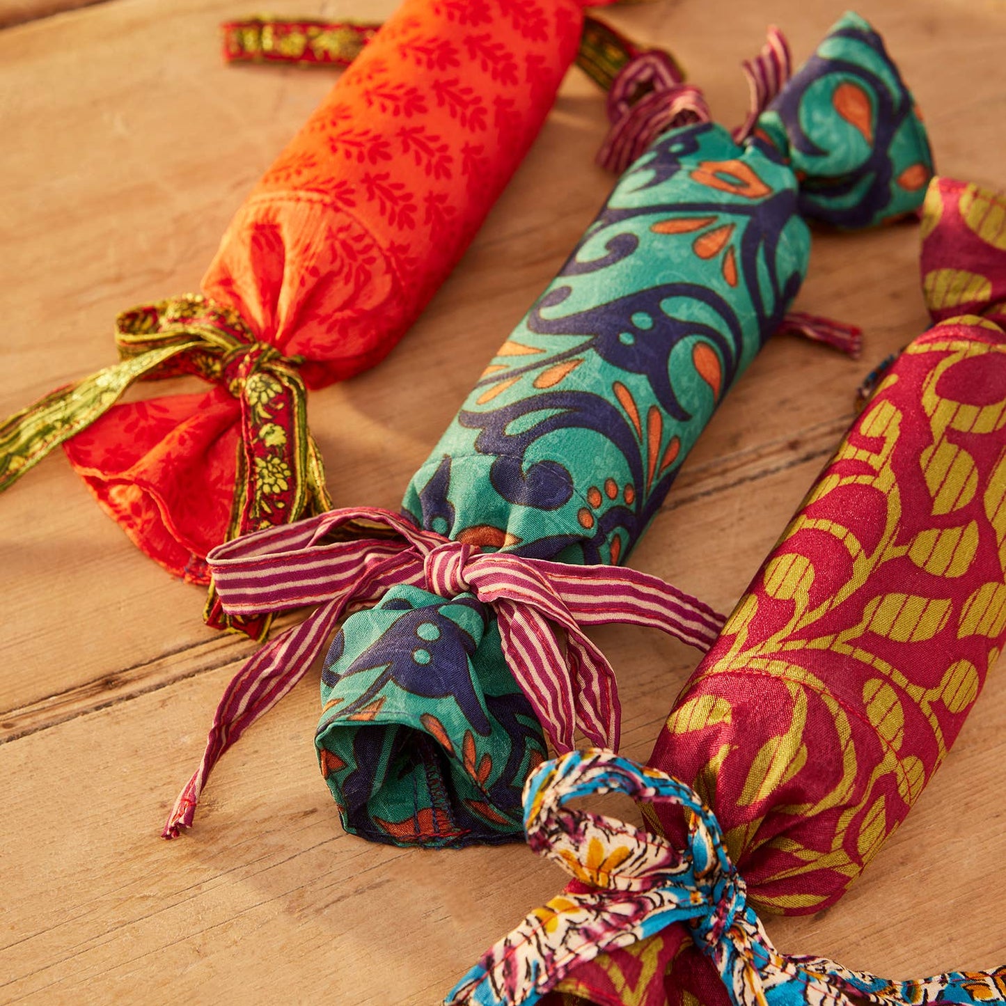 Colorful fabric-wrapped reusable saree christmas cracker on a wooden surface
