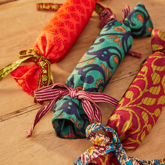 Colorful fabric-wrapped reusable saree christmas cracker on a wooden surface