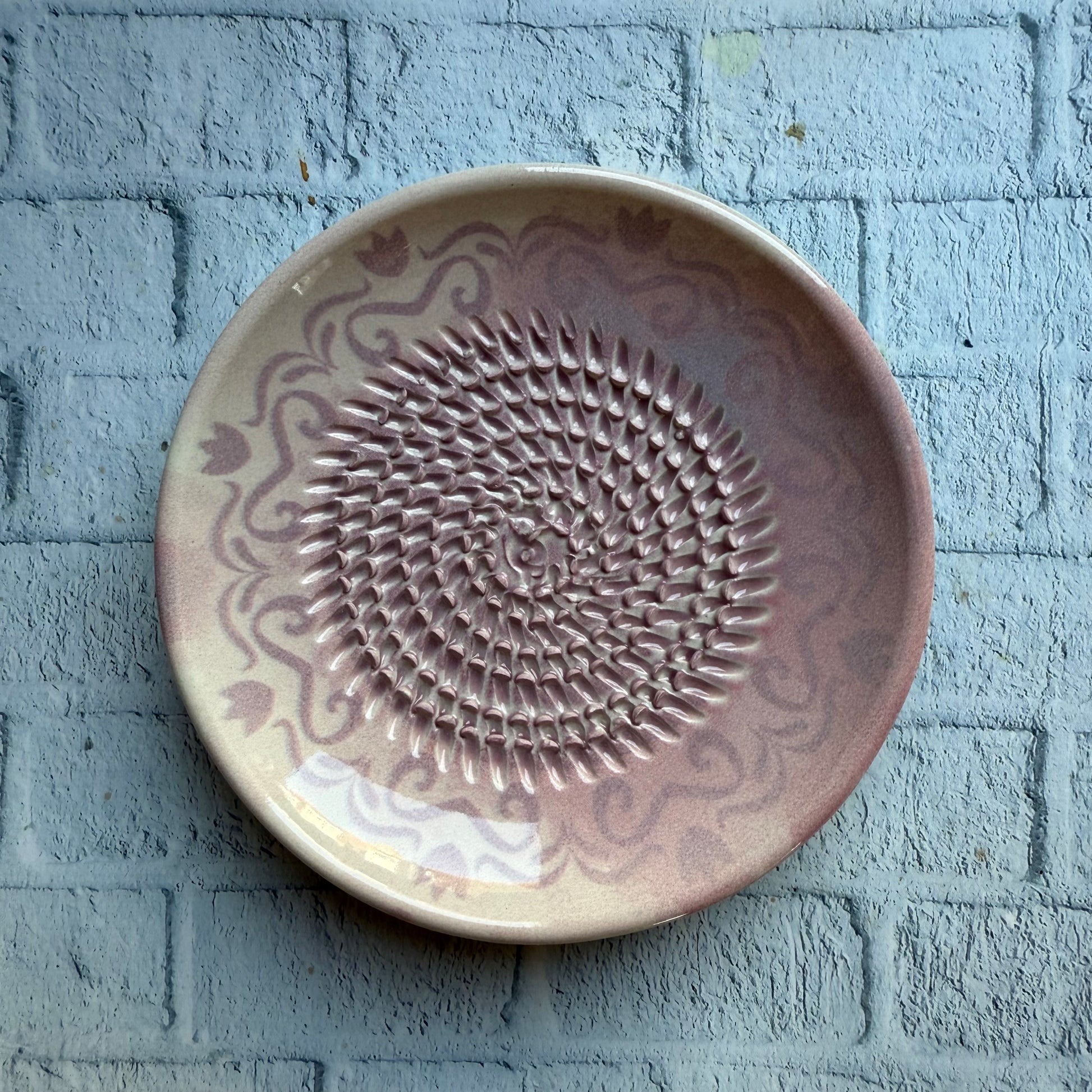 Ceramic plate with decorative pattern on a textured pale pink surface